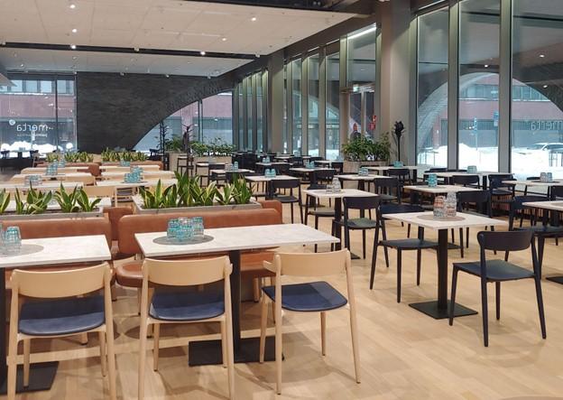 Photo of a canteen with several chairs and tables, the walls are made of glass.