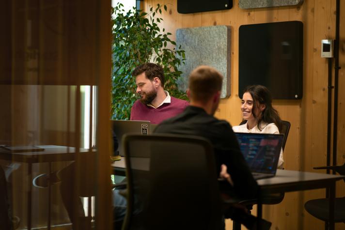 Photo of a group of people, working around a table with their notebooks