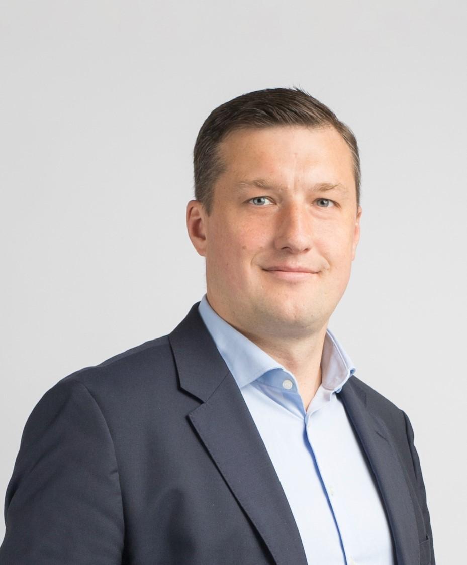 Photo of a man with a suit looking at the camera, smiling