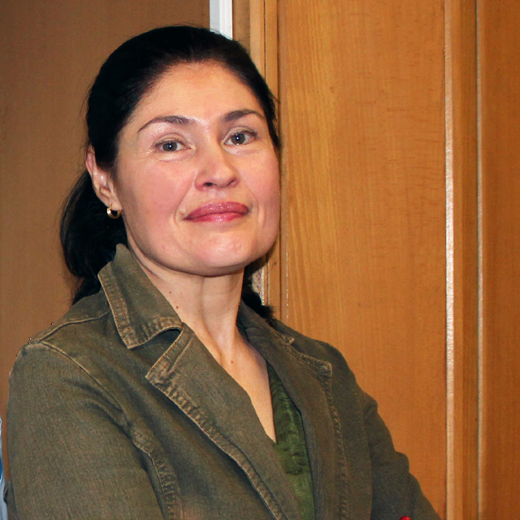 Photo of a woman looking at the camera, brunette, wearing a green jacket