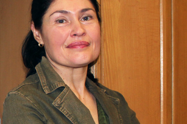 Photo of a woman looking at the camera, brunette, wearing a green jacket